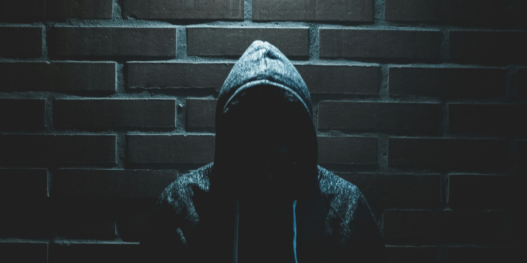 Apple working with British police to tackle iPhone theft | Photo shows a face hidden in darkness by a hoodie